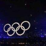 Olympics rings glitter over performers inside the stadium.